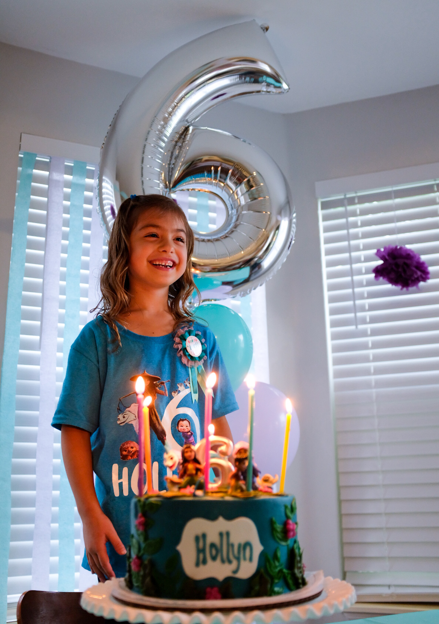 girl standing behind birthday cake